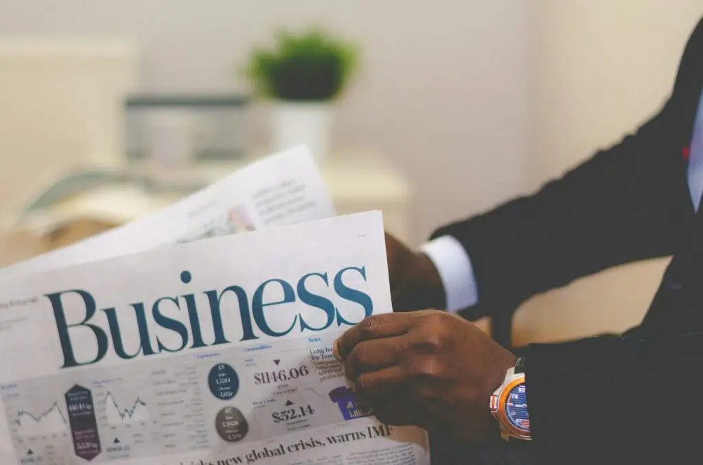 person wearing suit reading business newspaper