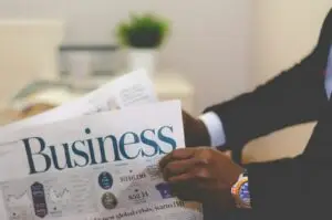 person wearing suit reading business newspaper