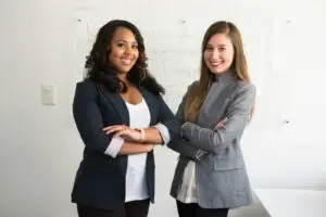 two women in suits standing beside wall